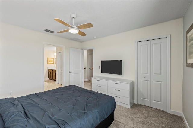 bedroom featuring ceiling fan, a closet, connected bathroom, and light carpet