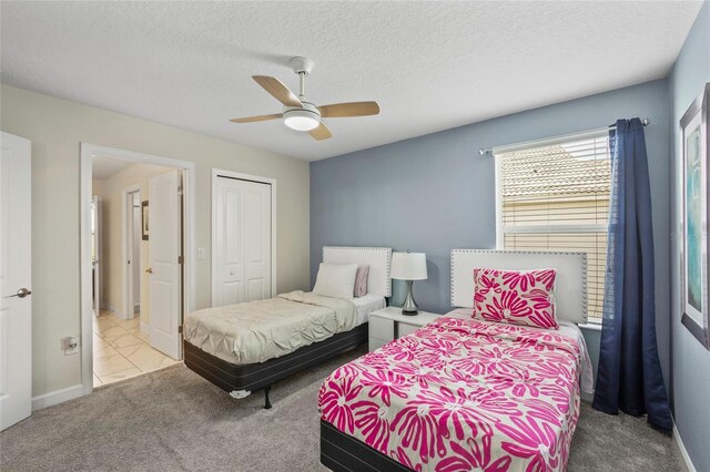 bedroom with ceiling fan, light colored carpet, a closet, and a textured ceiling