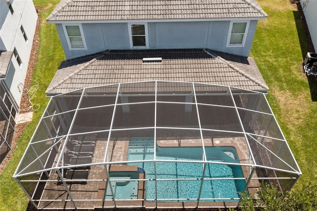 back of house featuring a swimming pool with hot tub, a patio, a yard, and glass enclosure