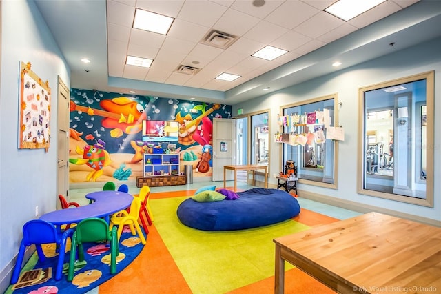 game room with a raised ceiling and a drop ceiling