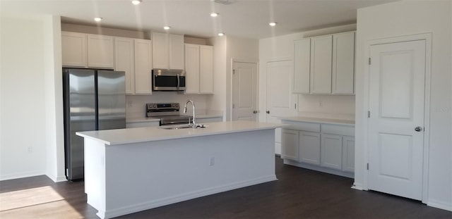 kitchen featuring sink, dark wood-type flooring, appliances with stainless steel finishes, an island with sink, and white cabinets