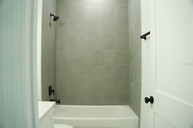 bathroom featuring tiled shower / bath combo and toilet