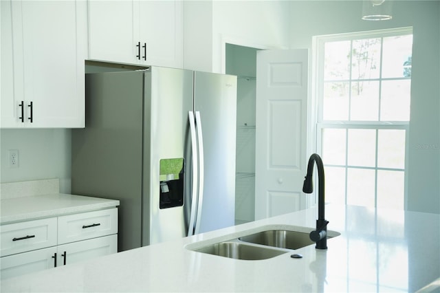 kitchen featuring white cabinets, stainless steel fridge, and sink