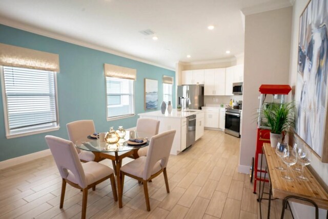 dining space with ornamental molding and light hardwood / wood-style flooring