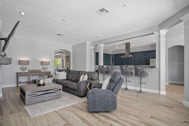 living room featuring ornate columns and light hardwood / wood-style floors