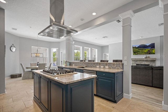 kitchen with light stone counters, a center island, stainless steel gas stovetop, light tile flooring, and island exhaust hood