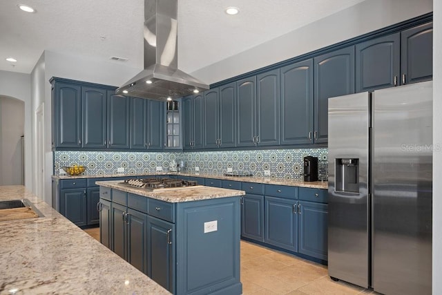 kitchen with tasteful backsplash, appliances with stainless steel finishes, island range hood, and blue cabinetry