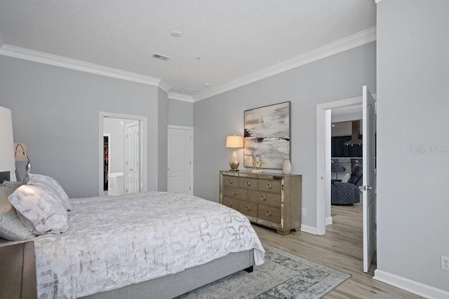 bedroom featuring connected bathroom, light hardwood / wood-style flooring, and crown molding