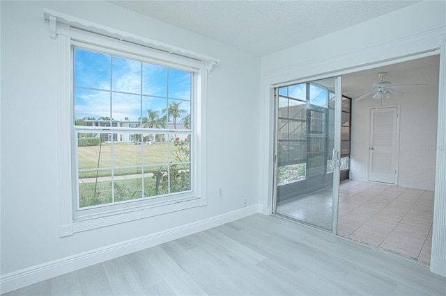 unfurnished room with ceiling fan, light hardwood / wood-style flooring, a wealth of natural light, and a textured ceiling