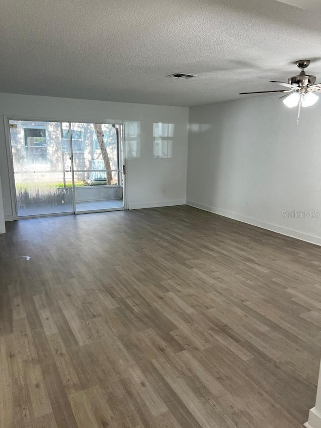 empty room featuring ceiling fan, dark hardwood / wood-style floors, and a textured ceiling