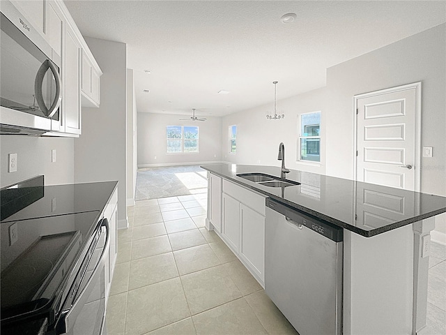 kitchen with sink, an island with sink, white cabinets, ceiling fan with notable chandelier, and appliances with stainless steel finishes