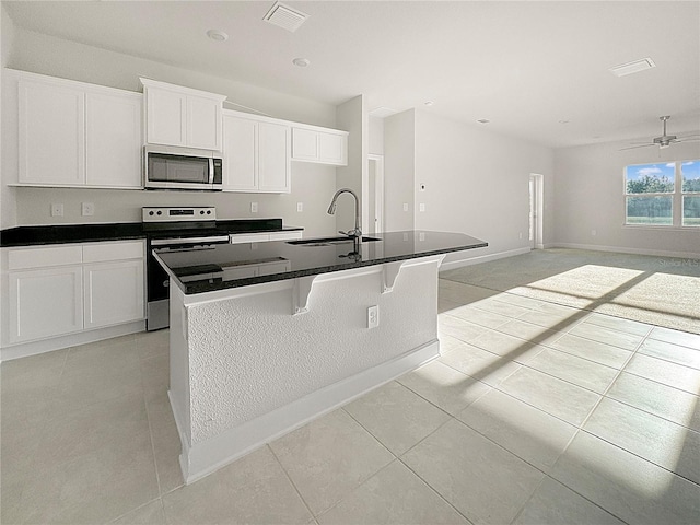 kitchen featuring a kitchen island with sink, a sink, visible vents, appliances with stainless steel finishes, and dark countertops