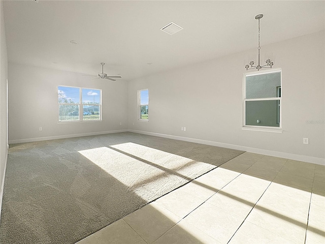 carpeted spare room with ceiling fan with notable chandelier