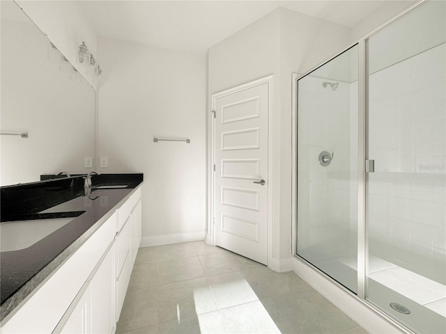 bathroom featuring a stall shower, tile patterned flooring, a sink, and baseboards