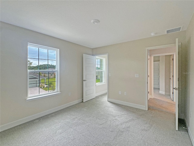 unfurnished room featuring carpet floors, baseboards, visible vents, and a textured ceiling