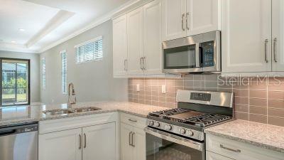 kitchen with white cabinetry, sink, light stone countertops, tasteful backsplash, and appliances with stainless steel finishes