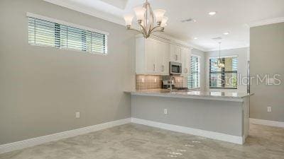 kitchen with white cabinetry, a healthy amount of sunlight, decorative light fixtures, and an inviting chandelier