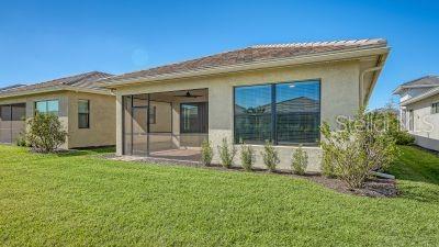 back of property with a lawn and a sunroom