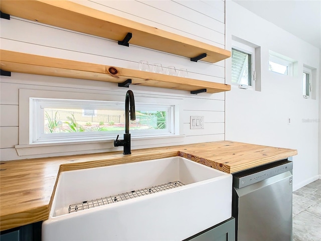 kitchen featuring sink, butcher block countertops, and stainless steel dishwasher