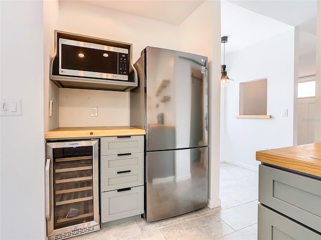 kitchen featuring light tile flooring, beverage cooler, gray cabinetry, fridge, and pendant lighting