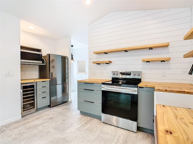 kitchen with wine cooler, stainless steel appliances, lofted ceiling, and wooden counters