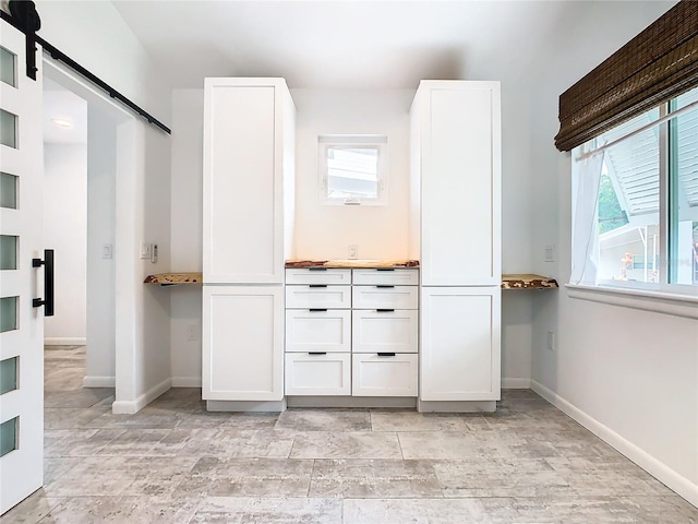 interior space featuring white cabinets, a barn door, and light tile flooring