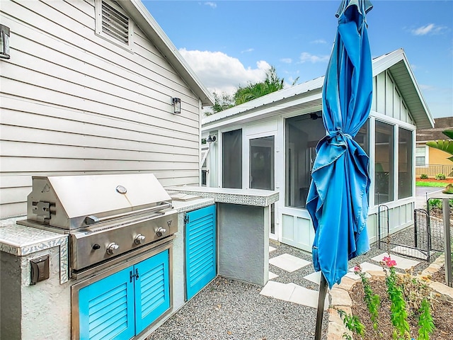 view of patio / terrace featuring a sunroom, exterior kitchen, and area for grilling