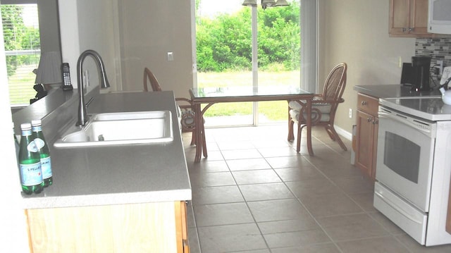 kitchen featuring tasteful backsplash, sink, tile patterned flooring, and white appliances