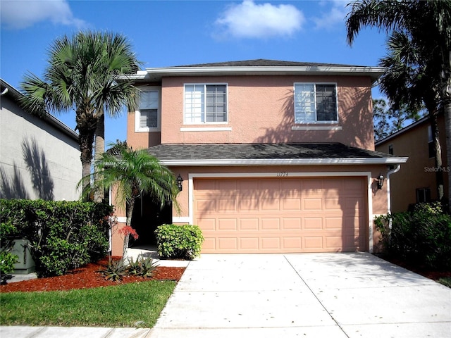 traditional home with stucco siding, an attached garage, concrete driveway, and a shingled roof