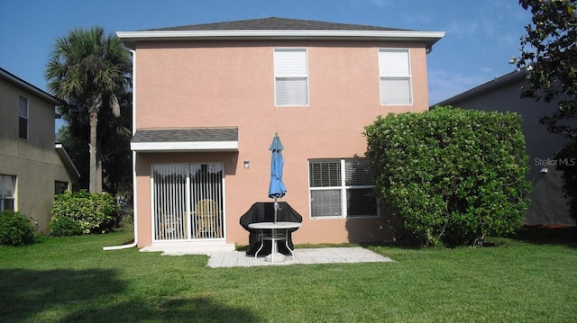 back of house featuring a patio area, a lawn, and stucco siding