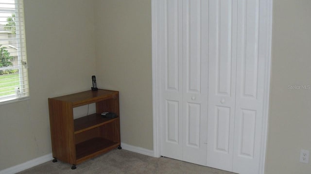 bedroom featuring baseboards, a closet, and light carpet