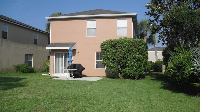 back of house featuring stucco siding, a lawn, a patio, and a shingled roof