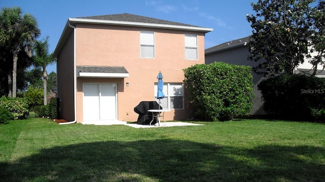 rear view of house featuring a patio area, a lawn, and stucco siding