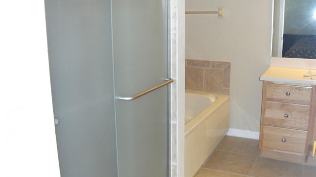 bathroom with a shower stall, tile patterned flooring, baseboards, a bath, and vanity