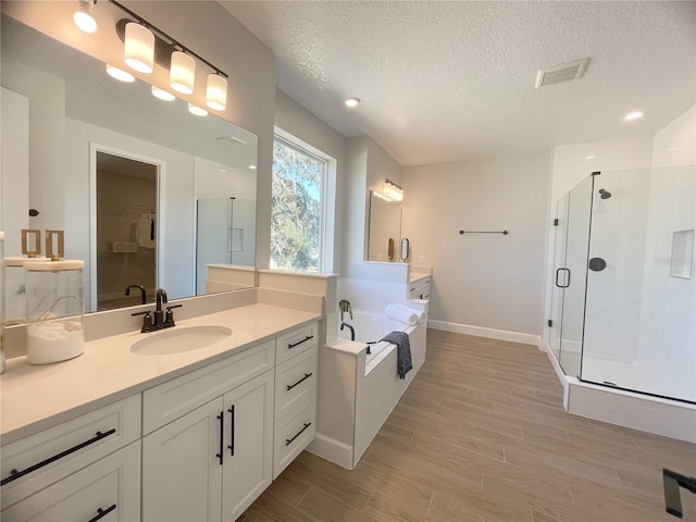 bathroom featuring vanity, a textured ceiling, and plus walk in shower