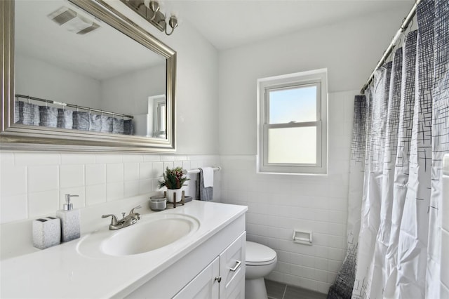 bathroom featuring vanity, toilet, and tile walls