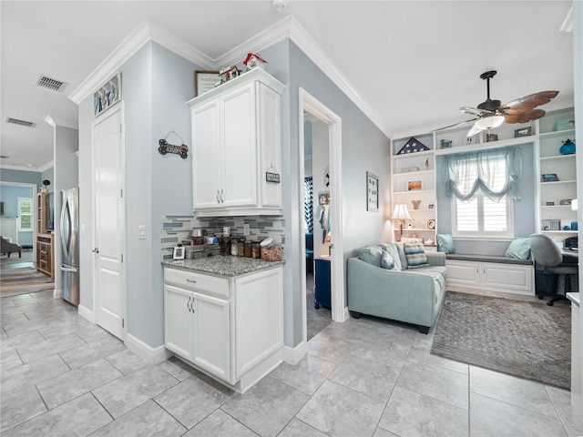 kitchen featuring ceiling fan, stainless steel fridge, backsplash, light tile floors, and ornamental molding