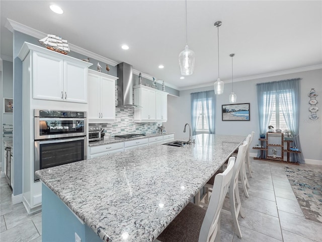 kitchen featuring tasteful backsplash, stainless steel appliances, a large island, wall chimney exhaust hood, and sink