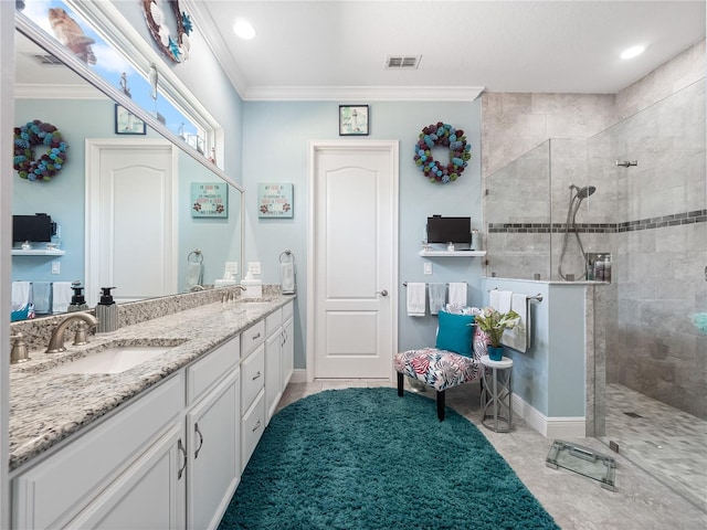 bathroom with tile flooring, tiled shower, double sink, vanity with extensive cabinet space, and ornamental molding