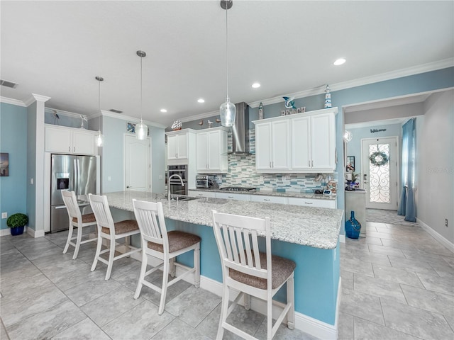 kitchen featuring decorative light fixtures, light stone counters, stainless steel appliances, wall chimney exhaust hood, and a large island