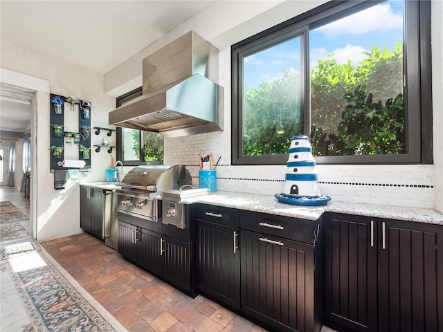 kitchen featuring a healthy amount of sunlight, exhaust hood, and backsplash