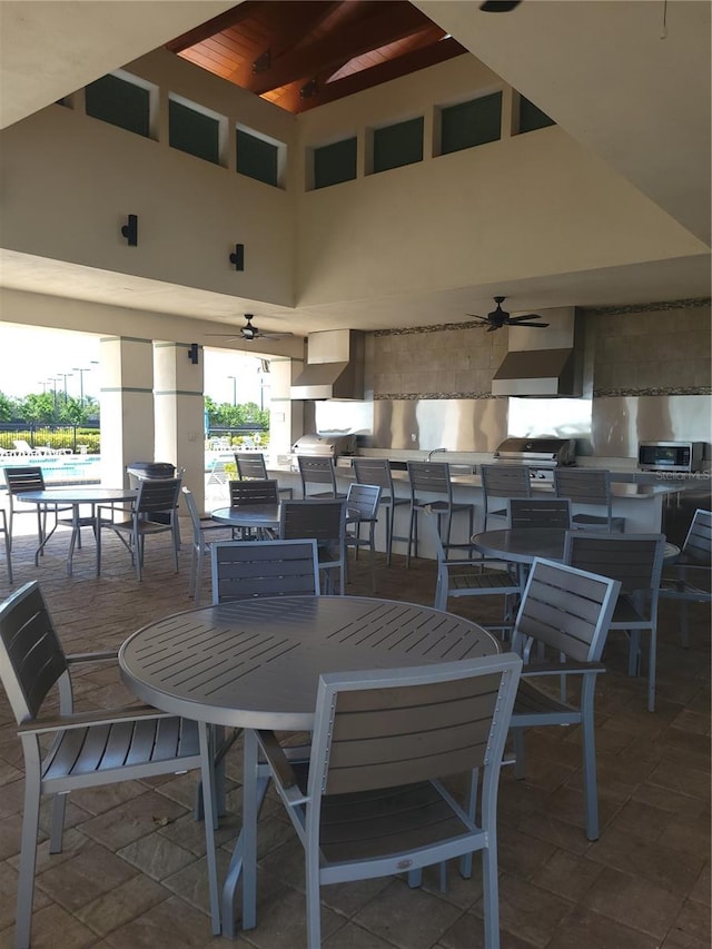 dining space with a towering ceiling, tile flooring, and ceiling fan