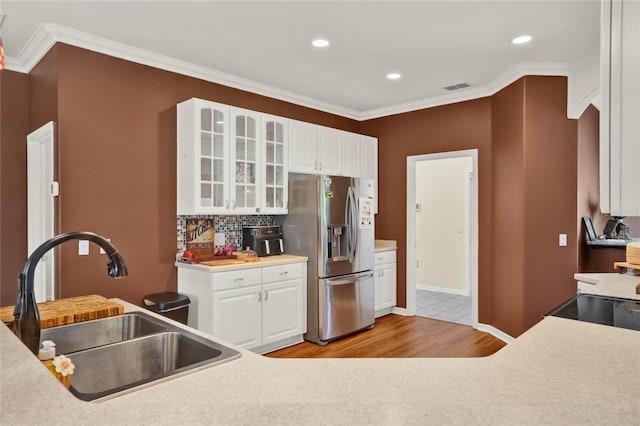 kitchen with light hardwood / wood-style floors, white cabinets, backsplash, stainless steel refrigerator with ice dispenser, and sink