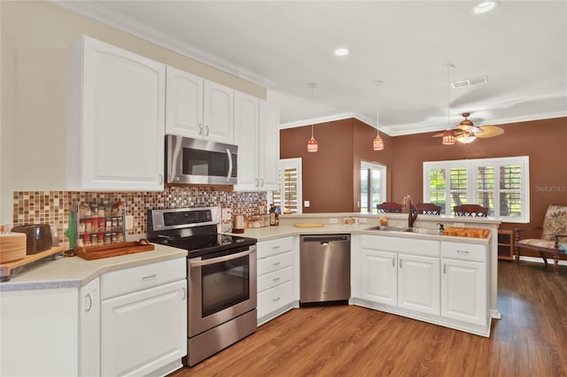 kitchen with light hardwood / wood-style floors, stainless steel appliances, kitchen peninsula, decorative light fixtures, and ceiling fan