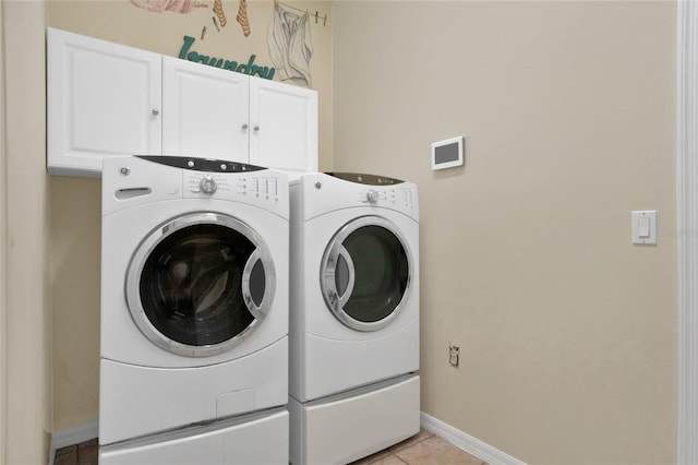 washroom featuring independent washer and dryer, light tile floors, and cabinets