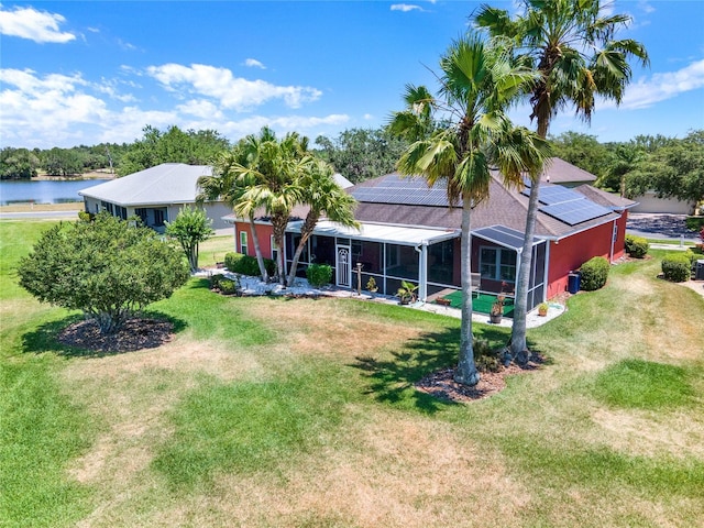 back of house with a yard, a water view, and solar panels