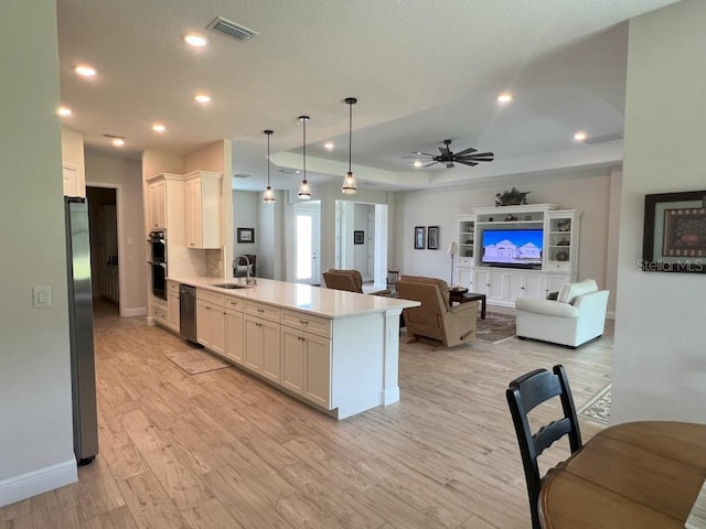 kitchen featuring hanging light fixtures, appliances with stainless steel finishes, sink, and white cabinets