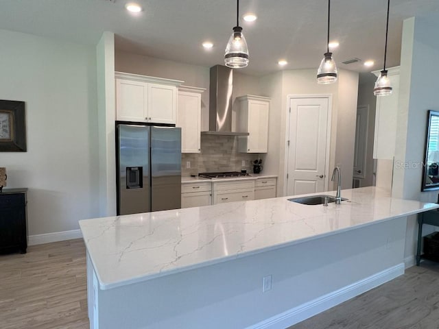 kitchen with stainless steel appliances, decorative light fixtures, white cabinets, and wall chimney exhaust hood