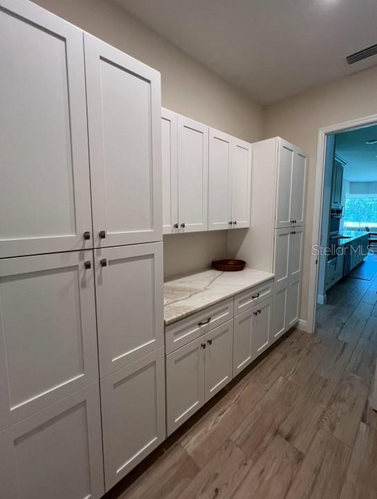 kitchen with dark hardwood / wood-style floors, white cabinets, and light stone counters