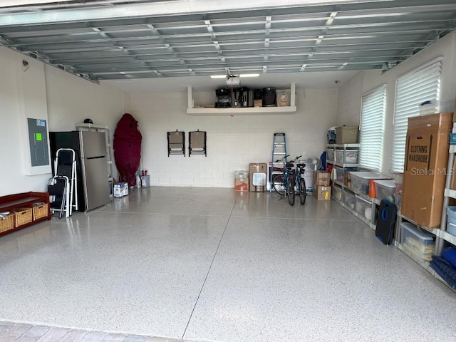 3962 Kennebunk Loop, Mount Dora, FL 32757 - garage with freestanding refrigerator, a garage door opener, electric panel, and concrete block wall